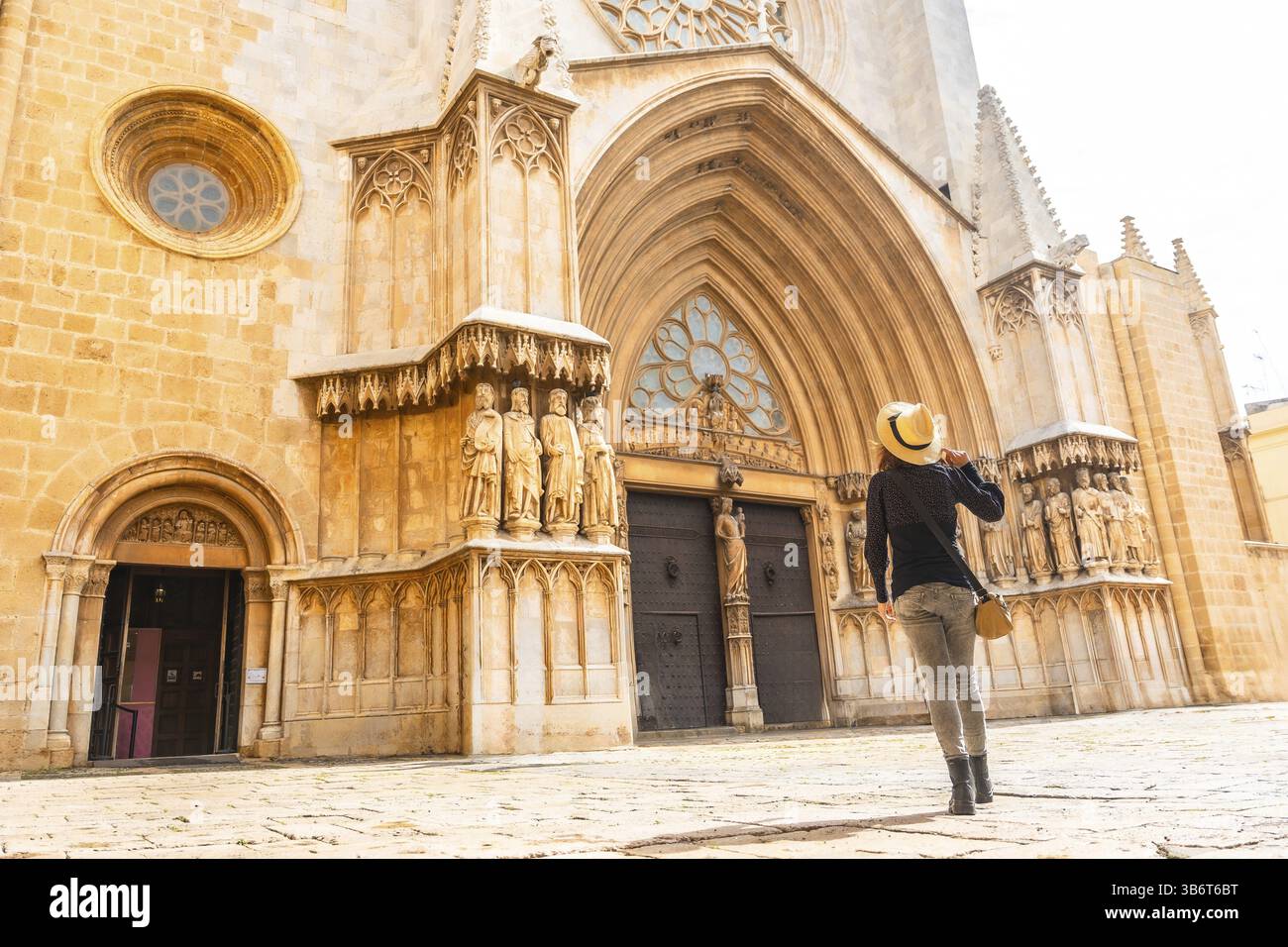 Camminando ammirando la splendida facciata medievale della cattedrale di tarragona nella soleggiata catalogna, immergendosi nella ricca storia e architettura Foto Stock