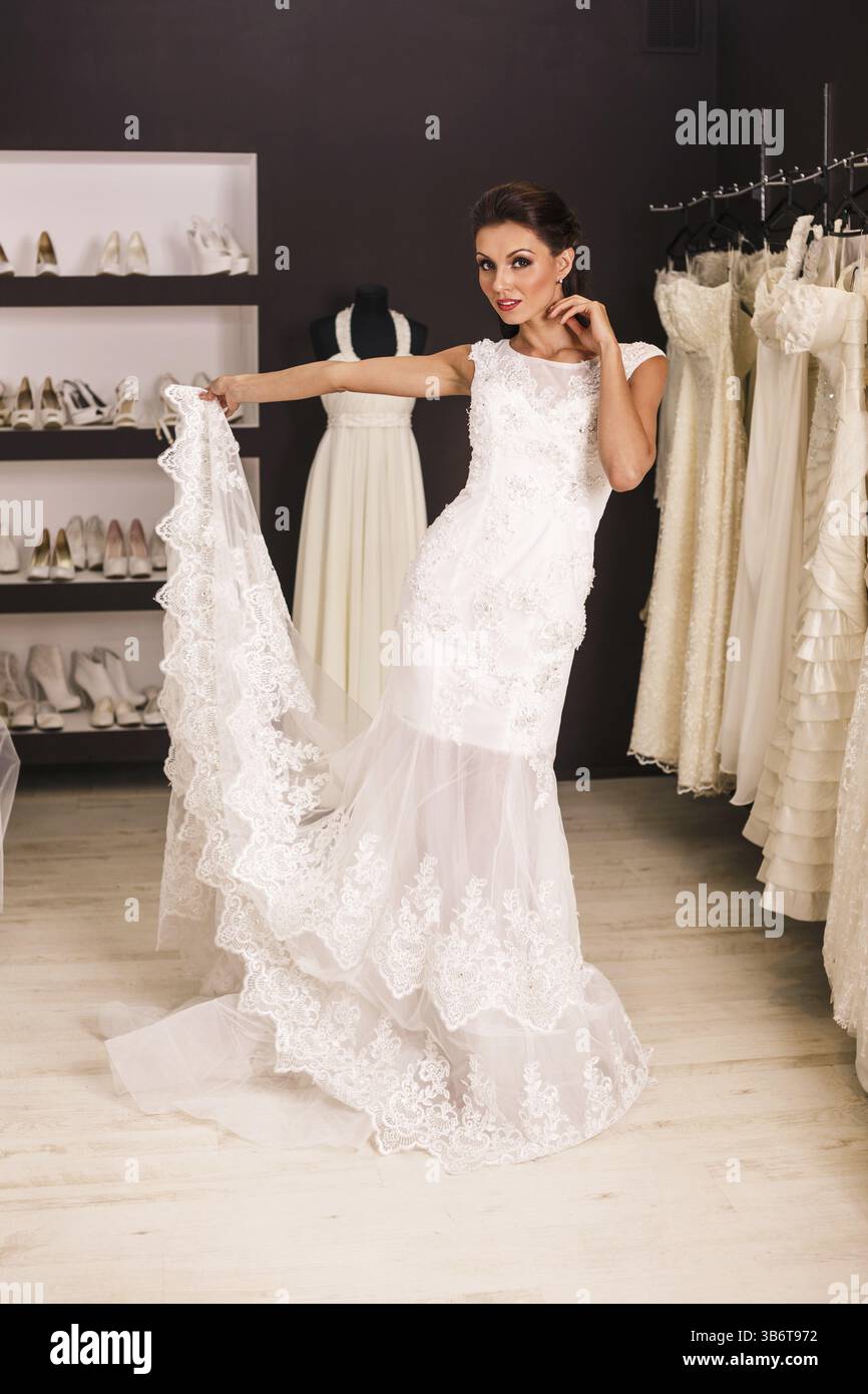 Giovane e bella sposa che prova il suo vestito in negozio Foto Stock