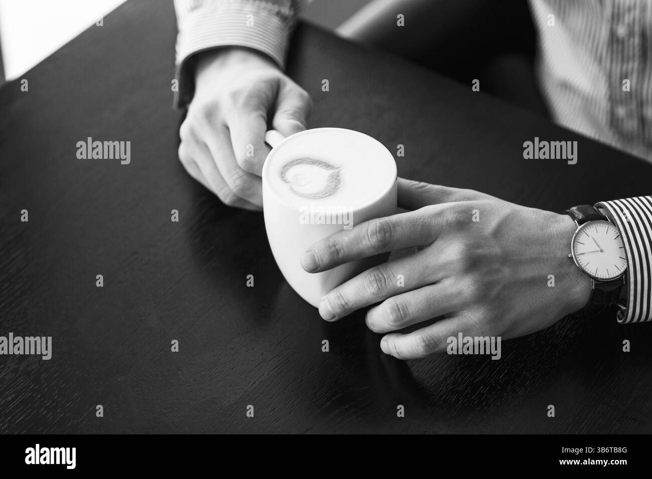 Imprenditore prendendo una pausa in ufficio come egli gode di una tazza calda di caffè aromatico, vista ravvicinata delle sue mani Foto Stock