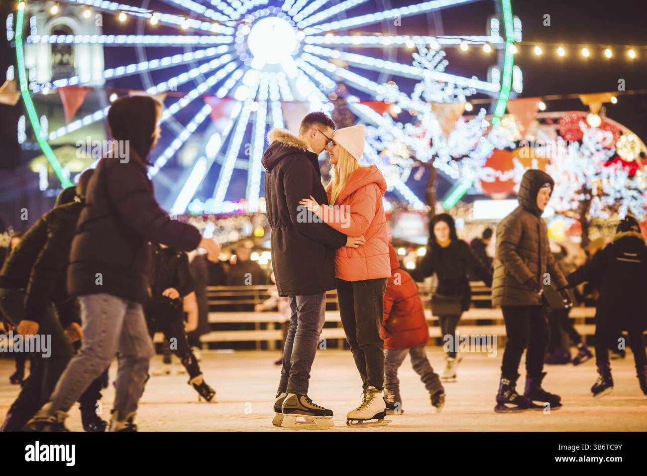 Coppia che abbraccia il giorno di San Valentino. Giovane coppia romantica che si diverte all'aperto in inverno. San Valentino sulla pista di pattinaggio su ghiaccio della città. Vacanze di Capodanno. a. Foto Stock