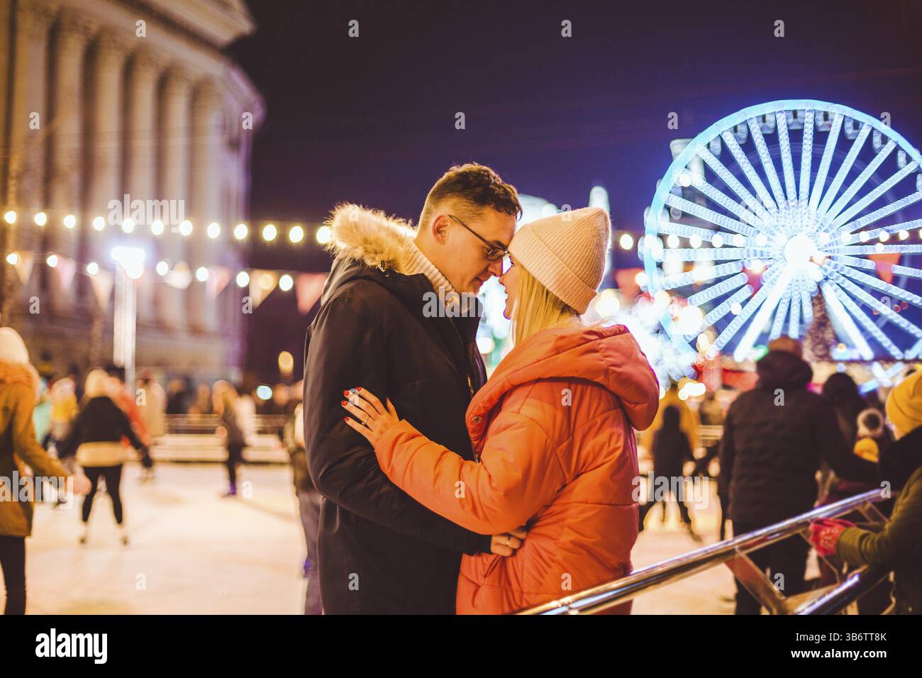 Coppia che abbraccia il giorno di San Valentino. Giovane coppia romantica che si diverte all'aperto in inverno. San Valentino sulla pista di pattinaggio su ghiaccio della città. Vacanze di Capodanno. a. Foto Stock