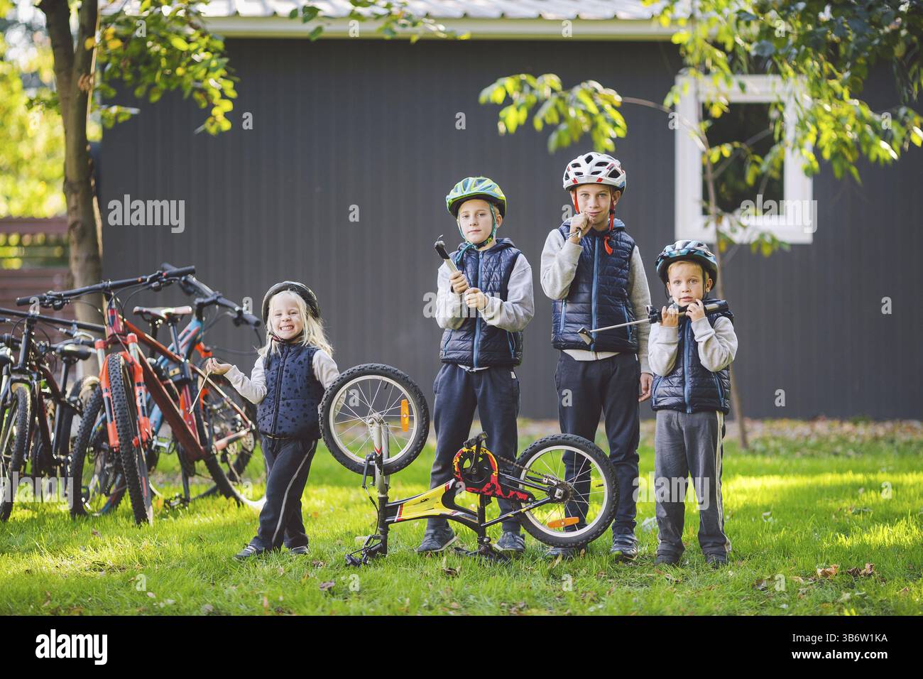Bambini meccanica, riparazione di biciclette. Contenti i bambini che fissa bike insieme all'aperto nella giornata di sole. Riparazione di biciclette concept. Il lavoro di squadra famiglia in posa con strumenti f Foto Stock