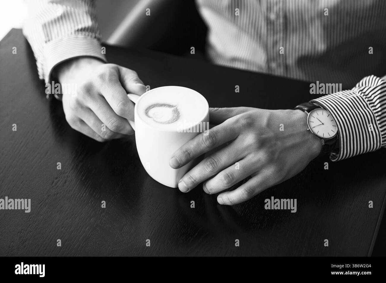 Imprenditore prendendo una pausa in ufficio come egli gode di una tazza calda di caffè aromatico, vista ravvicinata delle sue mani Foto Stock