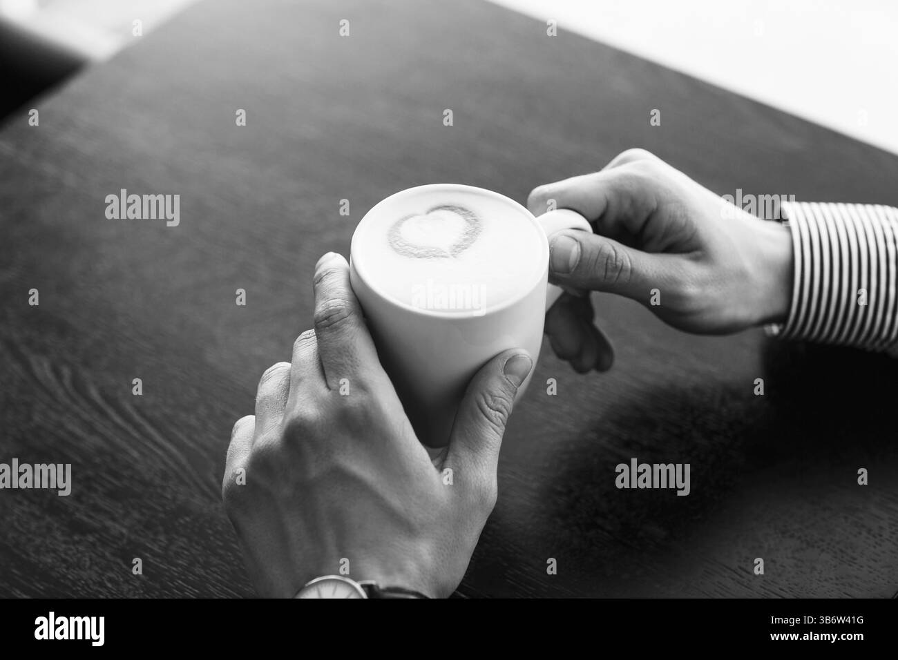 Imprenditore prendendo una pausa in ufficio come egli gode di una tazza calda di caffè aromatico, vista ravvicinata delle sue mani Foto Stock