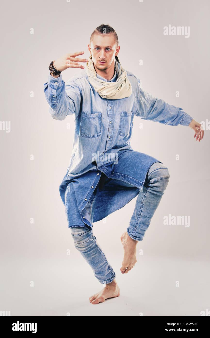 Ballerino maschile caucasico che indossa camicia e pantaloni blu in denim su sfondo chiaro che esegue hip hop e danza contemporanea, Toronto, Canada, Nord A. Foto Stock