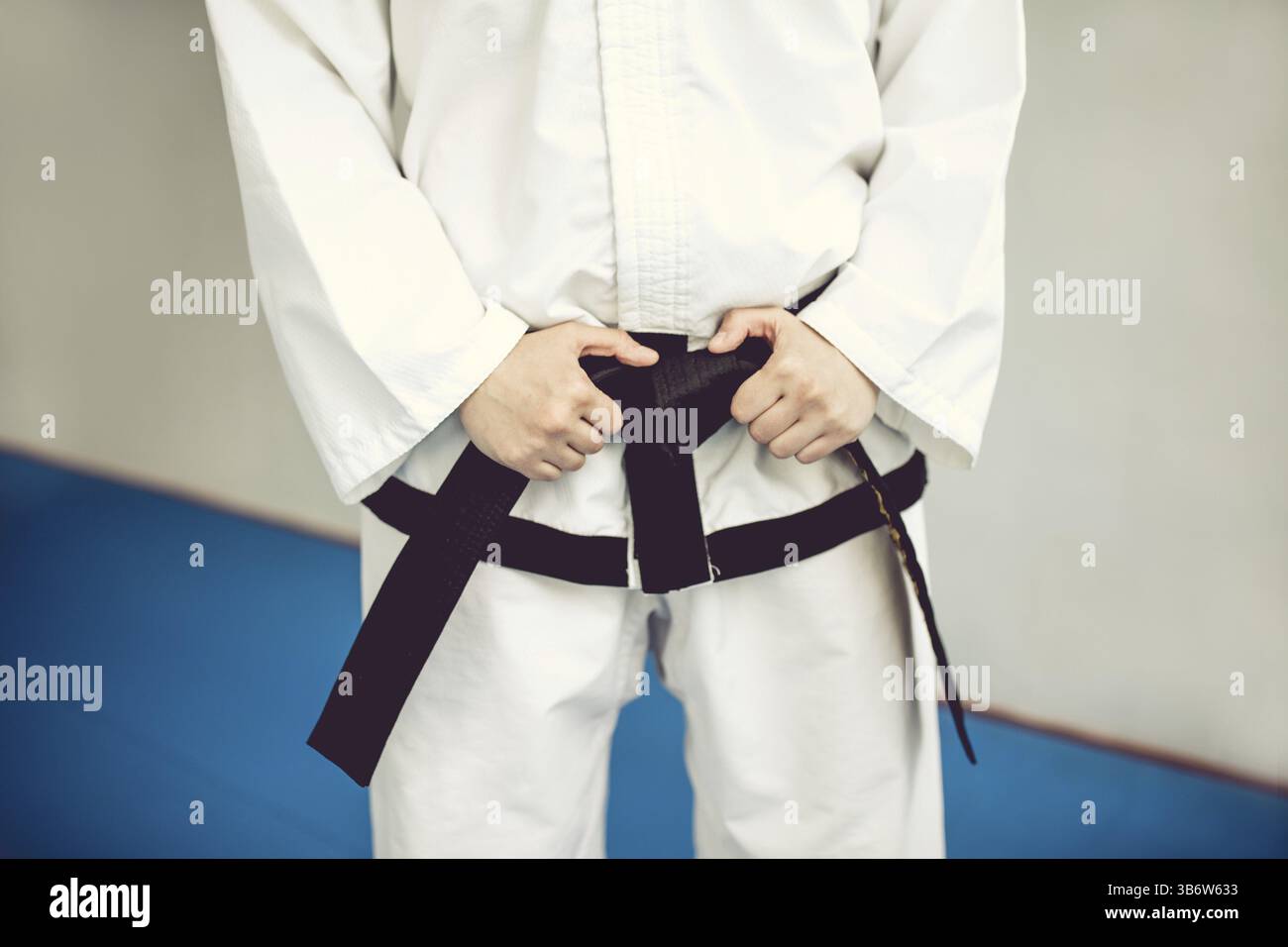 Mani sulla cintura nera e sul kimono. L'arte marziale di Tae Kwon Do e karate. Gente in palestra Foto Stock Mani sulla cintura nera e sul kimono. L'arte marziale di Tae Kwon Do e karate. Gente in palestra Foto Stock