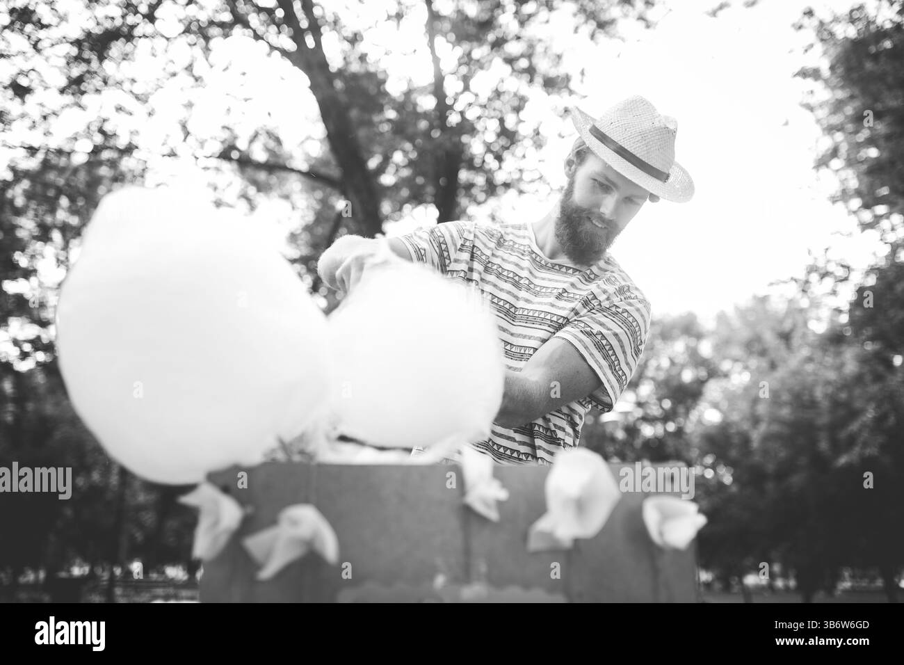 Tema fotografico dolci cucinati da piccole imprese. Un giovane con la barba di un commerciante caucasico nel cappello il proprietario dell'outlet fa filo interdentale di caramelle, fata Foto Stock