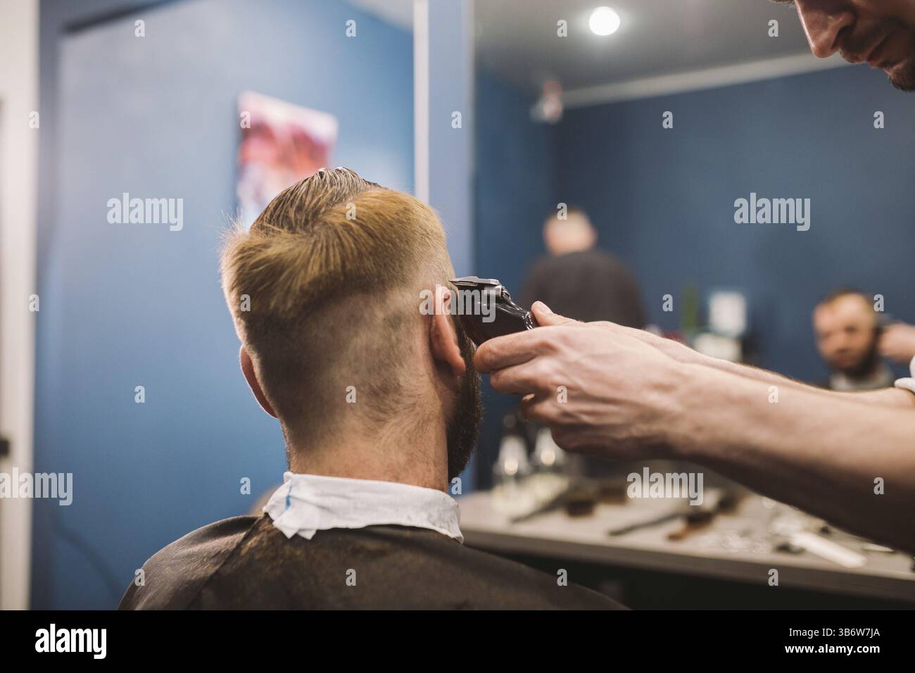 Immagine ravvicinata di un uomo di ottenere un taglio di capelli alla moda in un salone di parrucchiere. Maschio parrucchiere caucasici che serve un client. Con barba rendendo taglio di capelli con un t Foto Stock