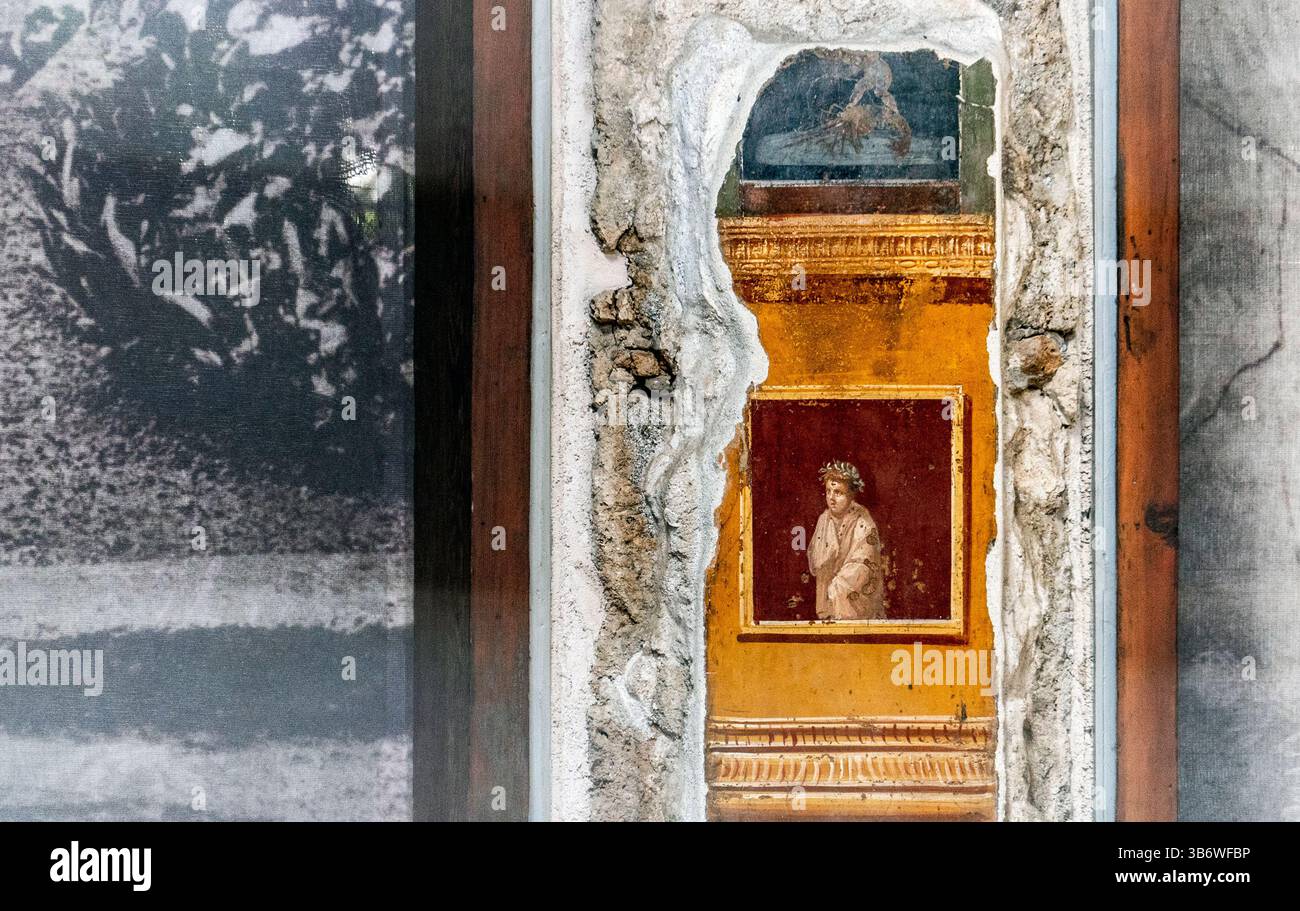 Una vista ravvicinata di un antico muro con un affresco parzialmente esposto, che mostra colori vivaci e dettagli intricati. L'area circostante mostra la luce Foto Stock