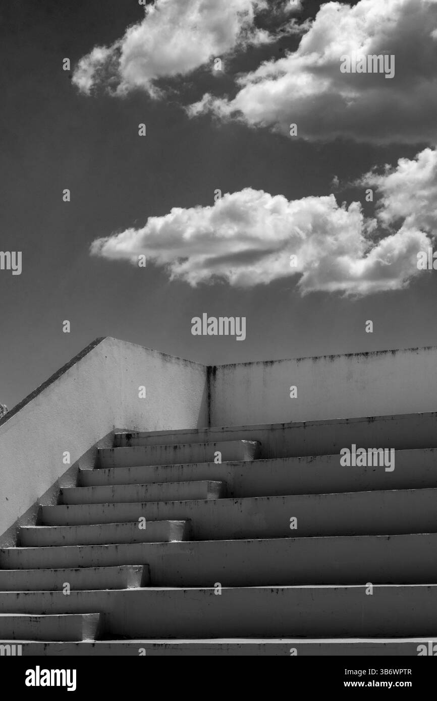 Passi verso il cielo: Nuvole sopra il cemento. Dettagli monocromatici. Foto Stock