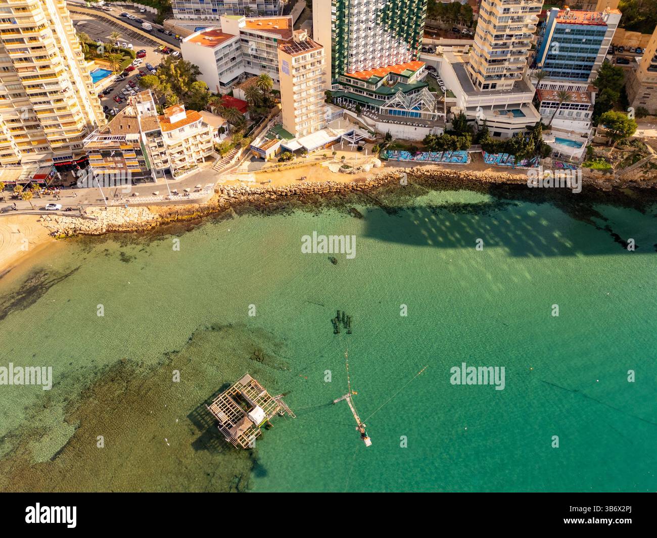 Una tranquilla vista aerea della spiaggia di Levante a Benidorm, Spagna, catturata durante la tranquilla stagione invernale. Il Mar Mediterraneo brilla sotto la luce soffusa del mattino, con pochi turisti in vista. Foto Stock