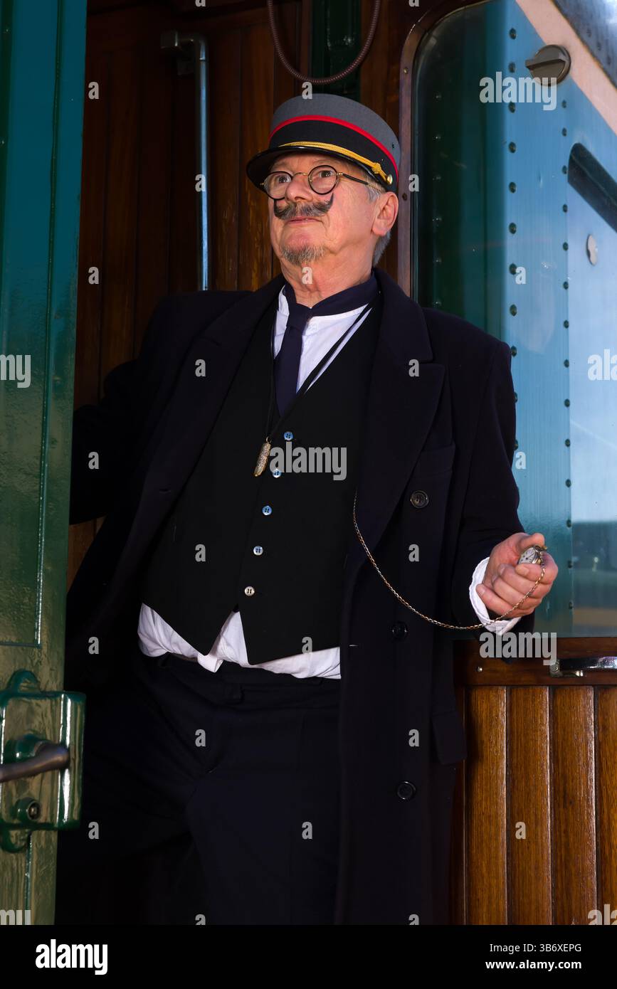 Scena di rievocazione di un conduttore ferroviario d'epoca alla partenza della carrozza ferroviaria di prima classe Foto Stock Scena di rievocazione di un conduttore ferroviario d'epoca alla partenza della carrozza ferroviaria di prima classe Foto Stock