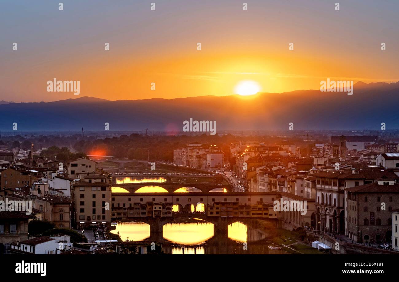 Uno splendido tramonto su Firenze, in Italia, che mostra il fiume Arno e l'architettura storica. Il sole si getta dietro le montagne, dando un caldo bagliore Foto Stock