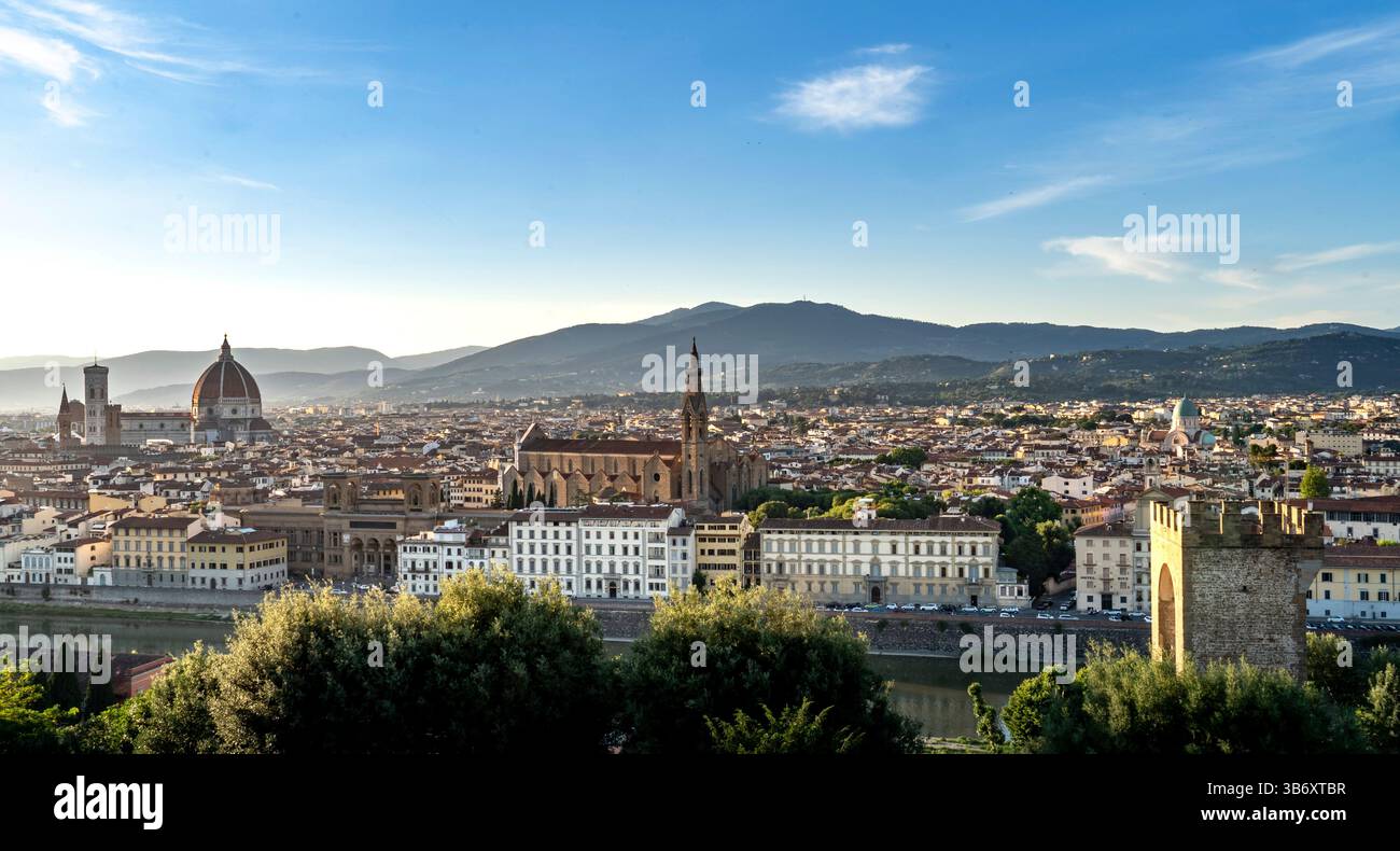 Una vista panoramica di Firenze, Italia, che mostra l'iconico skyline con il Duomo, Palazzo Vecchio e il fiume Arno. La scena è immersa in caldo su Foto Stock