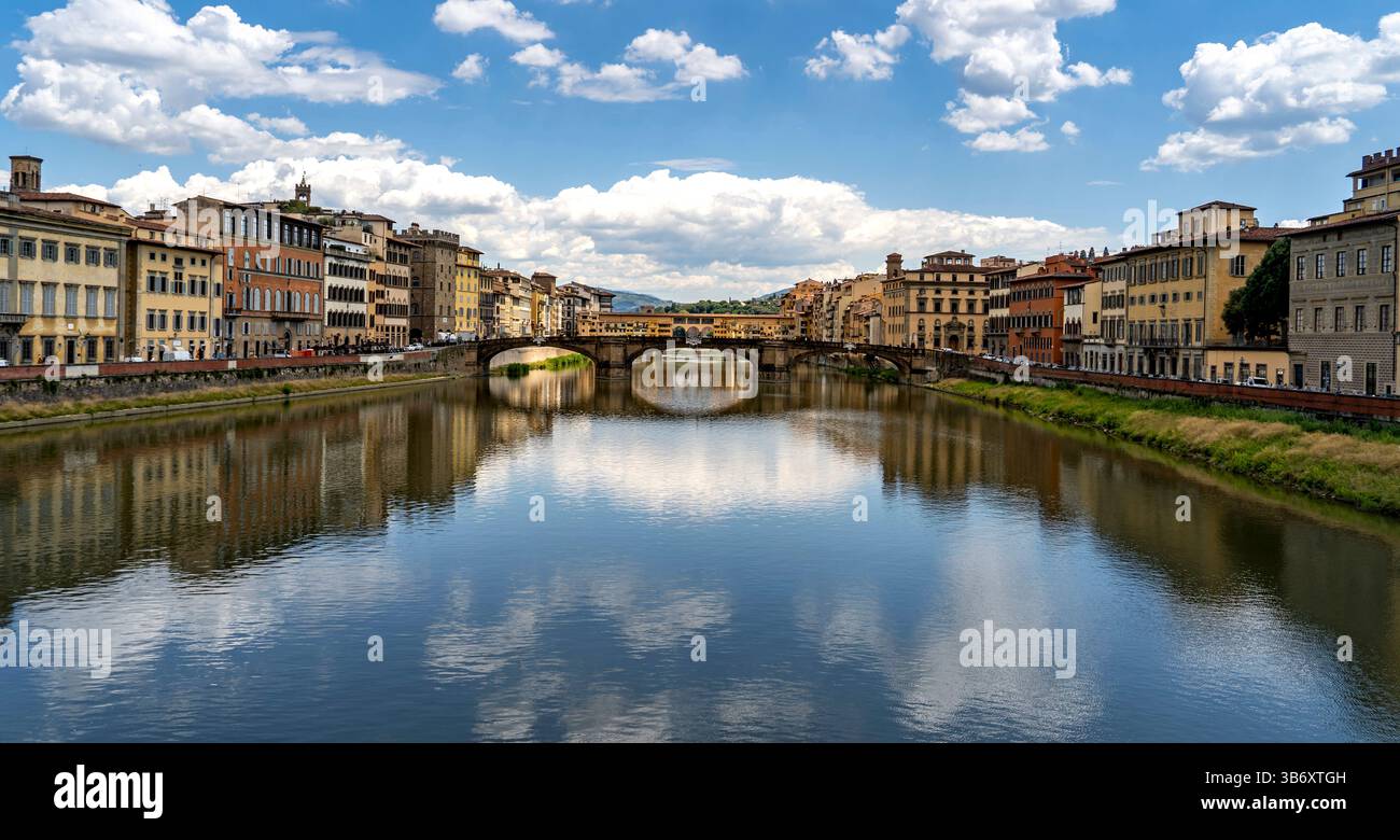 Una vista panoramica del fiume Arno a Firenze, in Italia, con edifici storici lungo le rive del fiume e un ponte che attraversa l'acqua. Il cielo è alla pari Foto Stock