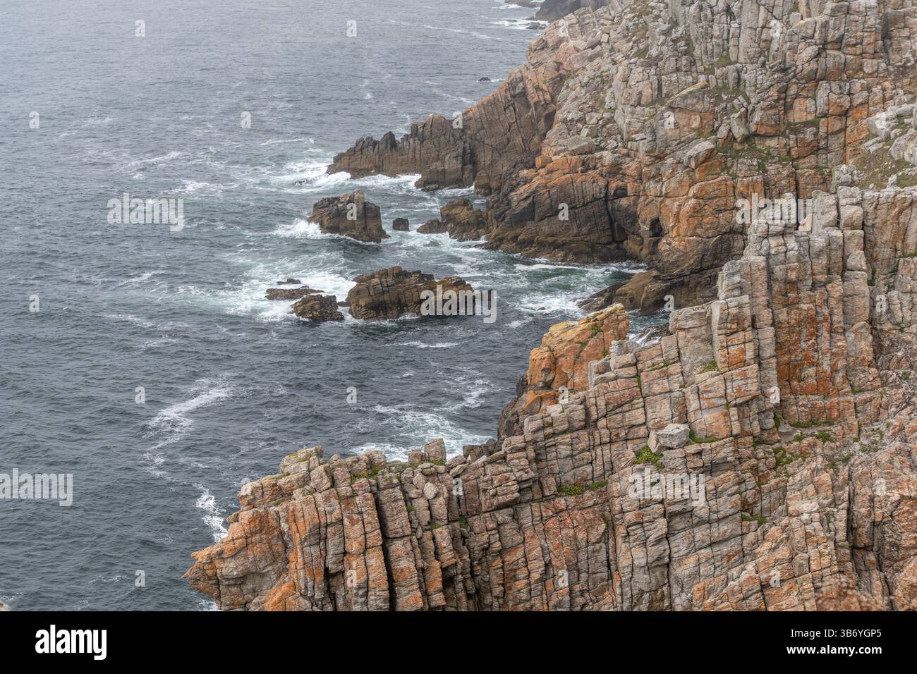 Una costa rocciosa con una scogliera rocciosa e un corpo d'acqua. L'acqua è instabile e le rocce sono arancioni. Camaret, Crozon, Finistere, Bretagne, Francia, Foto Stock