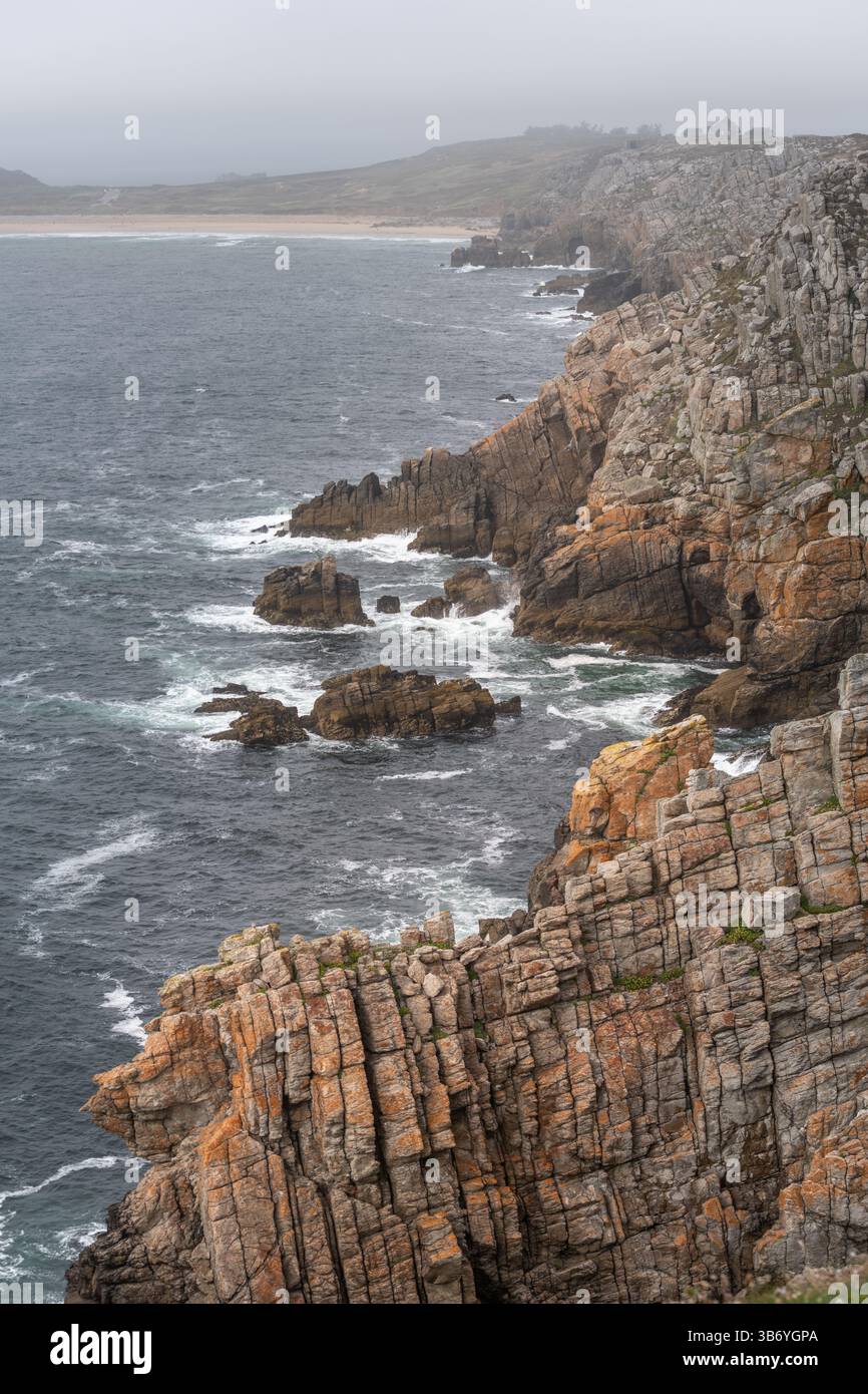 Una costa rocciosa con una scogliera rocciosa e un corpo d'acqua. L'acqua è instabile e le rocce sono arancioni. Camaret, Crozon, Finistere, Bretagne, Francia, Foto Stock