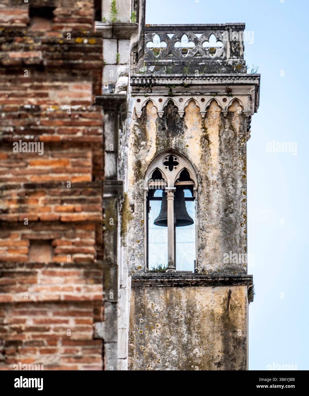 Una vista ravvicinata di un campanile intempestivo con dettagli architettonici intricati, caratterizzato da una campana visibile attraverso una finestra in stile gotico. La torre è p Foto Stock