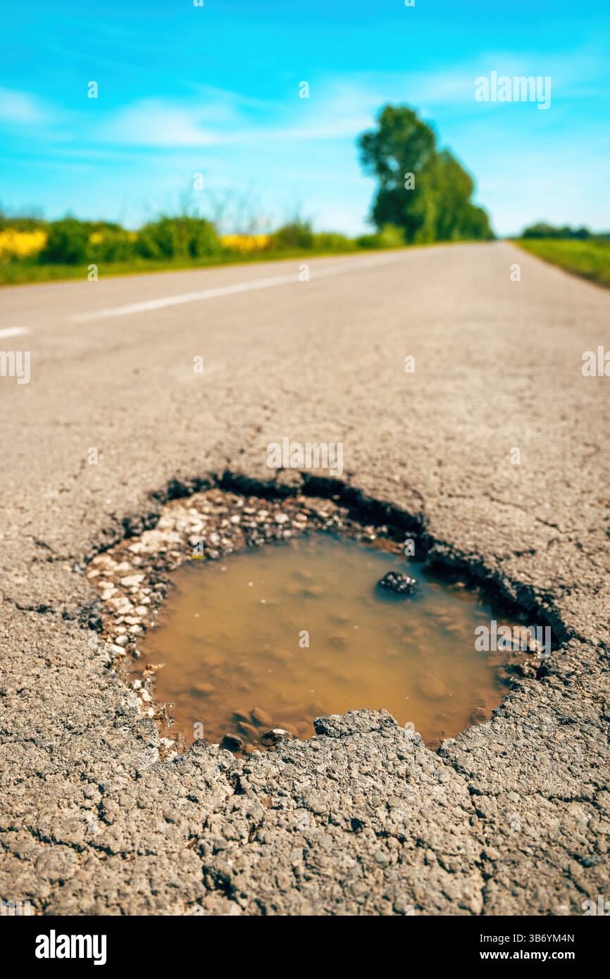 Grande foro su fondo stradale asfaltato, buco in una strada di campagna, attenzione selettiva Foto Stock