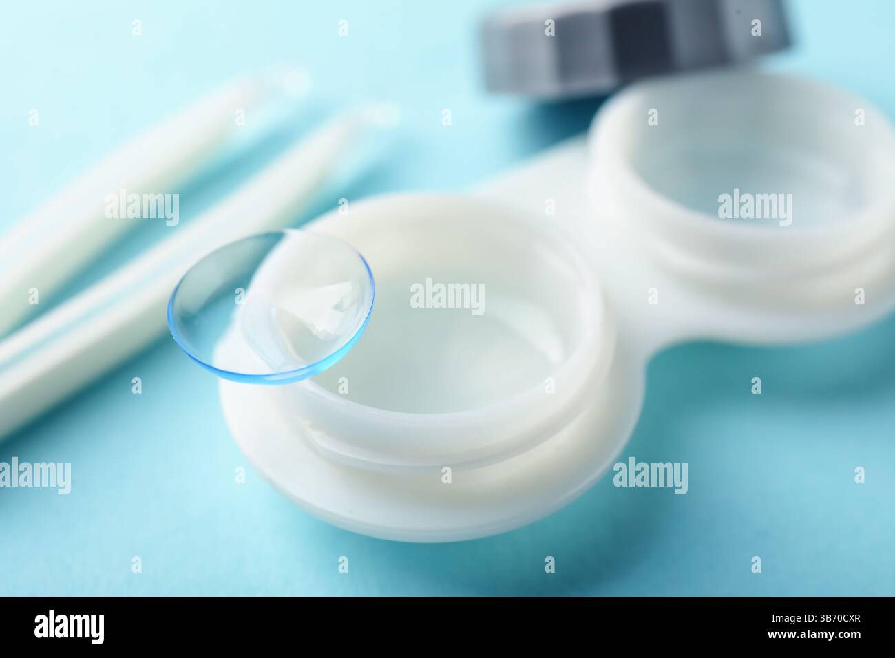 Lenti a contatto, custodia e pinzette su sfondo azzurro, primo piano Foto Stock