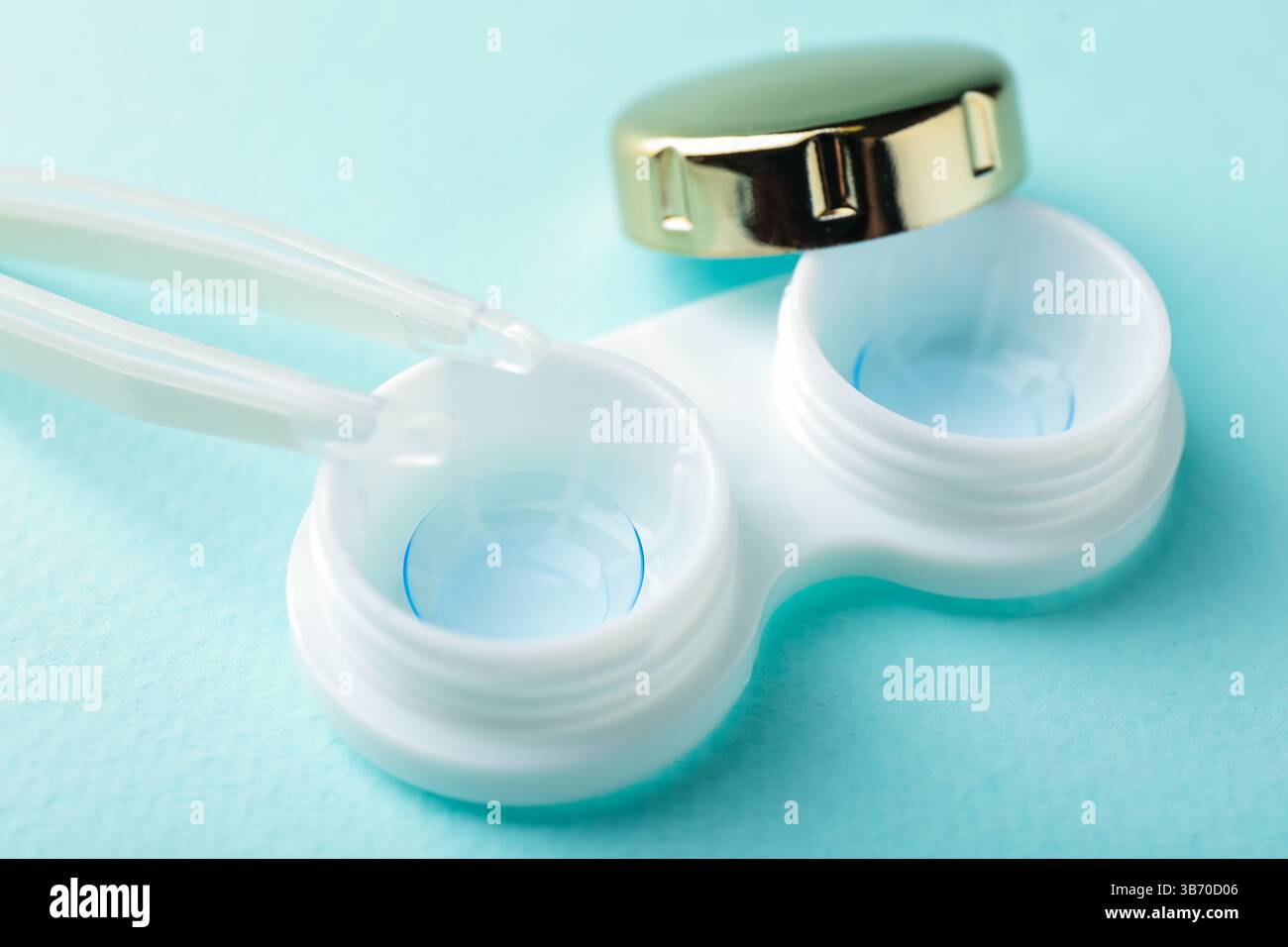 Lenti a contatto in astuccio e pinzette su sfondo turchese, primo piano Foto Stock