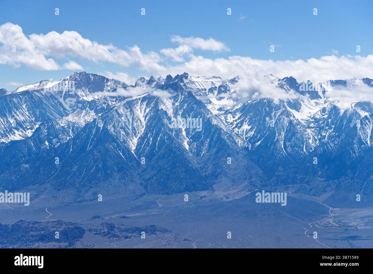 Il Monte Langley e altre High Sierra Mountains sono parzialmente avvolte da nuvole viste dalle Inyo Mountains attraverso la Owens Valley Foto Stock