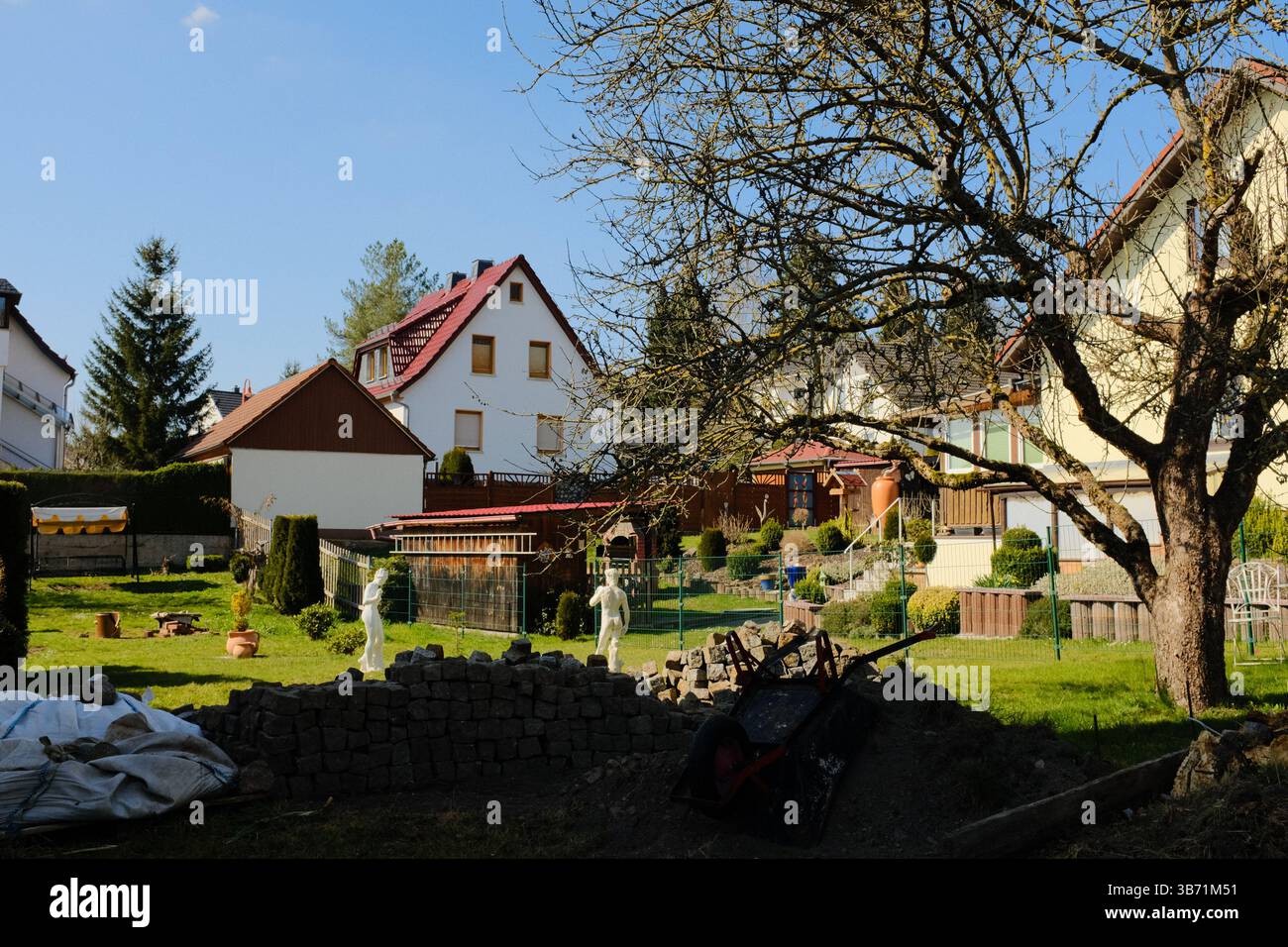 giardino del villaggio europeo decorato con statue bianche del coniglio pasquale e vegetazione primaverile sotto il cielo limpido. Foto di alta qualità Foto Stock