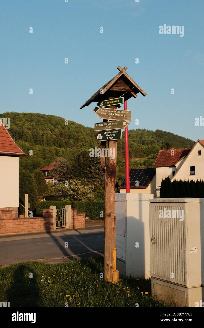 strada di campagna rurale con case campi verdi e alberi sotto il cielo blu in un tranquillo paesaggio paesaggistico all'ora d'oro. Foto di alta qualità Foto Stock