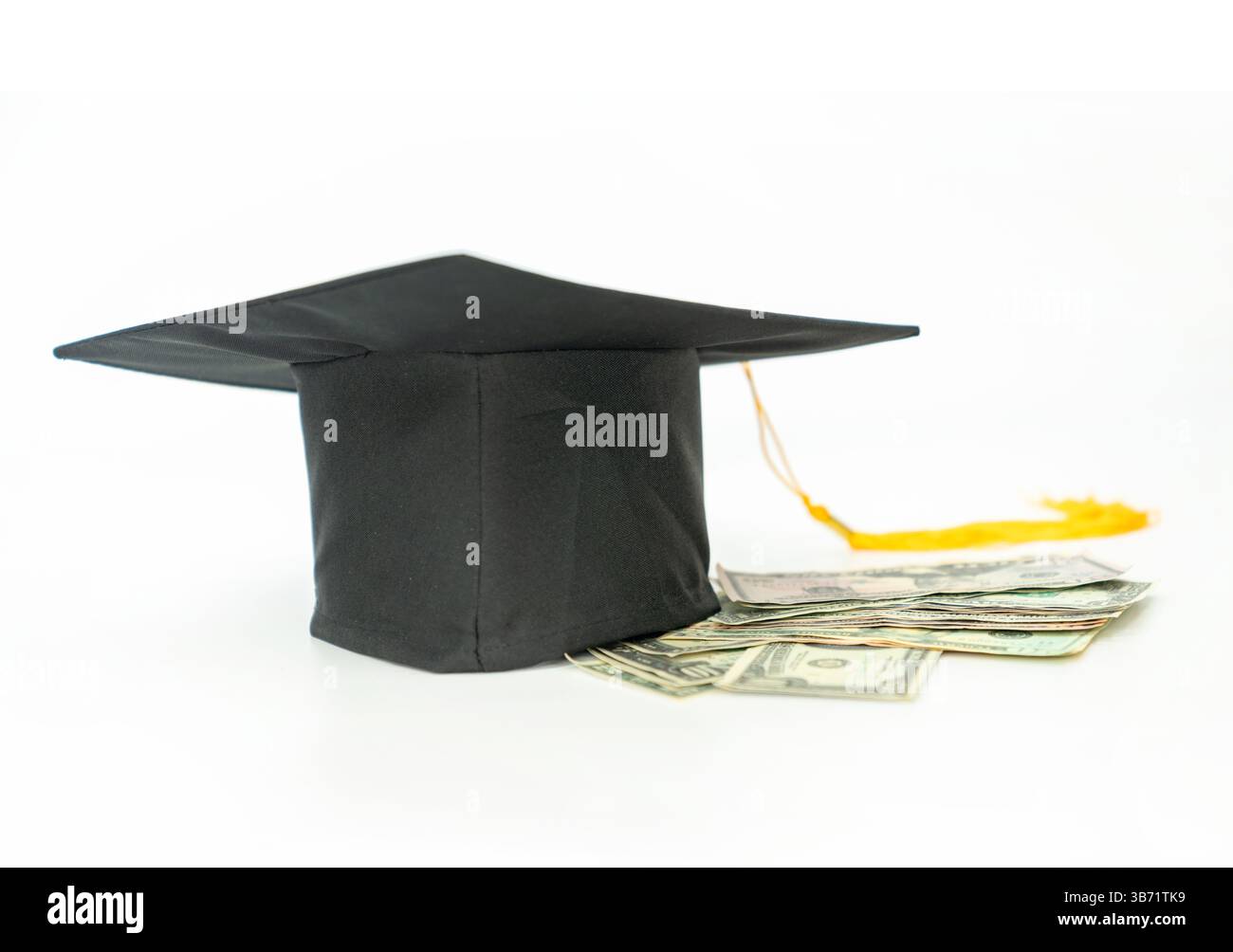 Mortarboard su banconota in dollari isolare su sfondo bianco, concetto di risparmio scolastico o prestito studentesco. Foto Stock
