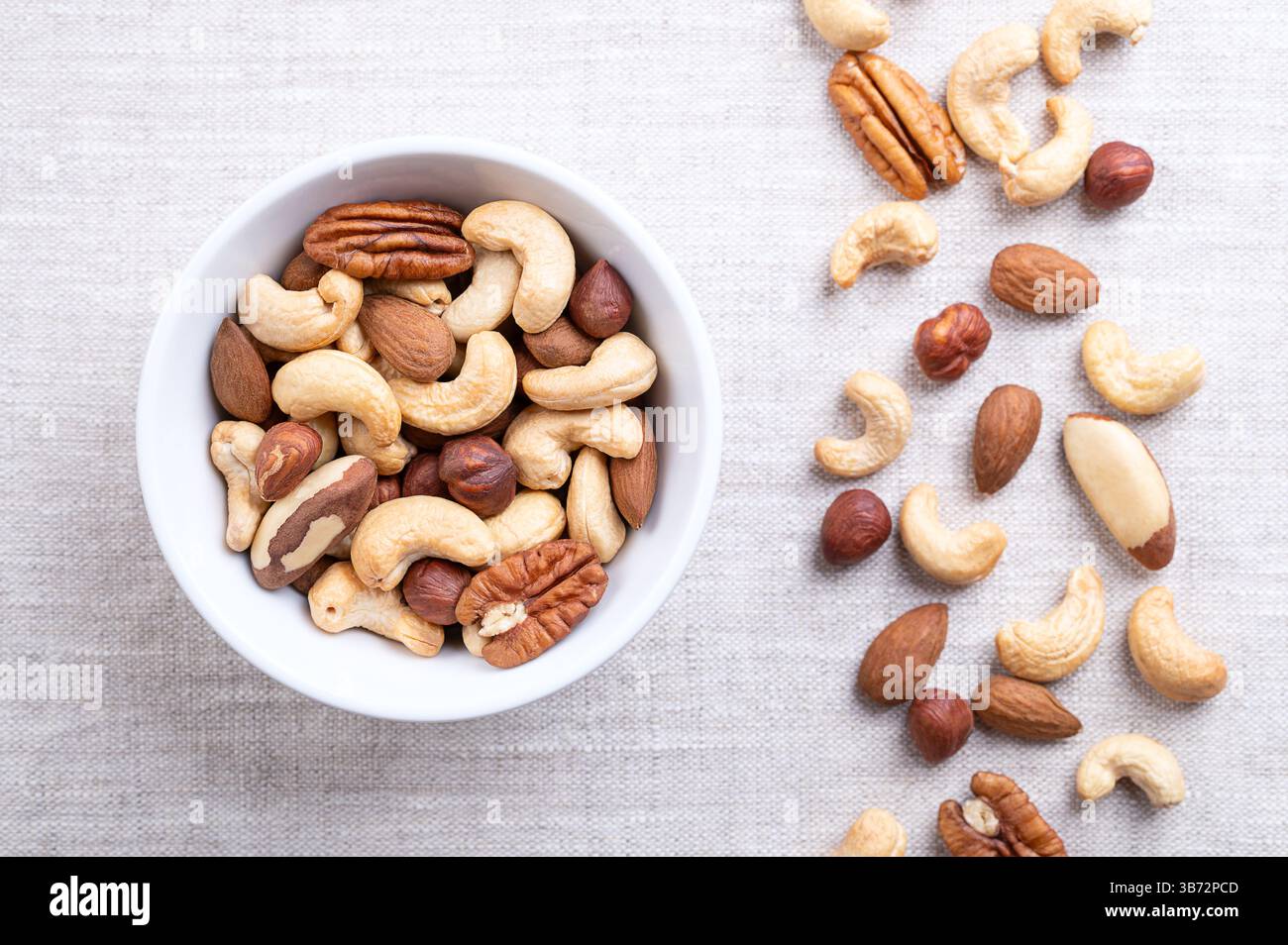 Noci tostate, croccante miscela di noci, spuntini veloci in un recipiente bianco di lino. Miscela di anacardi arrostiti, mandorle, nocciole, noci del Brasile e noci pecan. Foto Stock