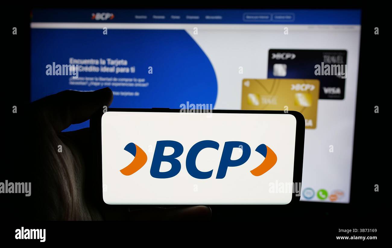 In questa foto, una persona ha in mano un cellulare con il logo del Banco de credito de Bolivia S.A. (BCP) sullo schermo davanti alla pagina web. Foto Stock