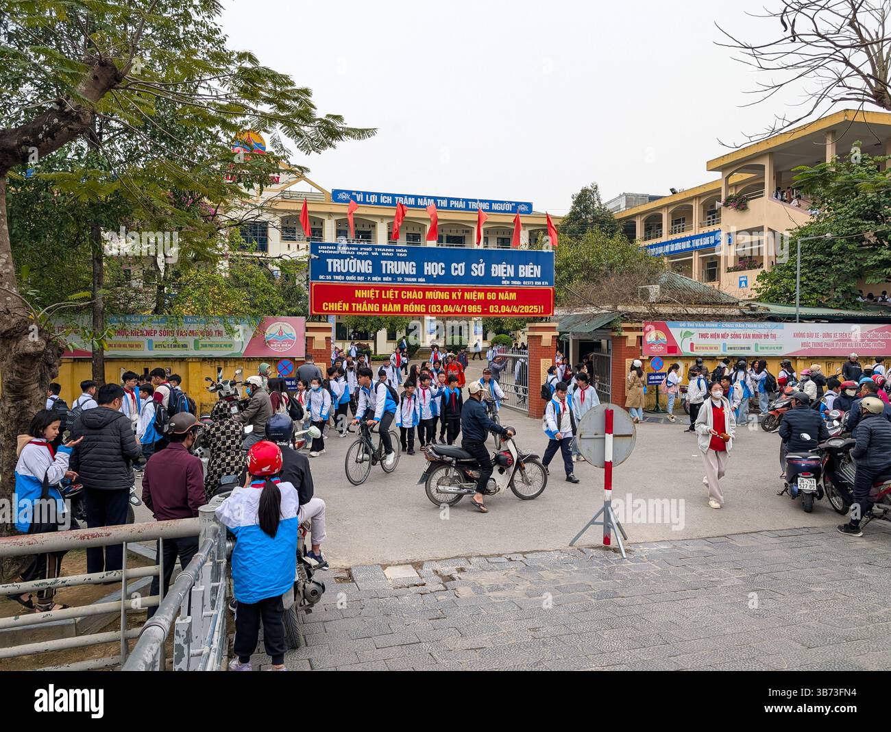 Gli studenti di una scuola media a Thanh Hoa, Vietnam, il 18 marzo 2025 lasciano la scuola dopo le lezioni. Gli alunni sono vestiti con uniformi bianche e blu. Foto Stock