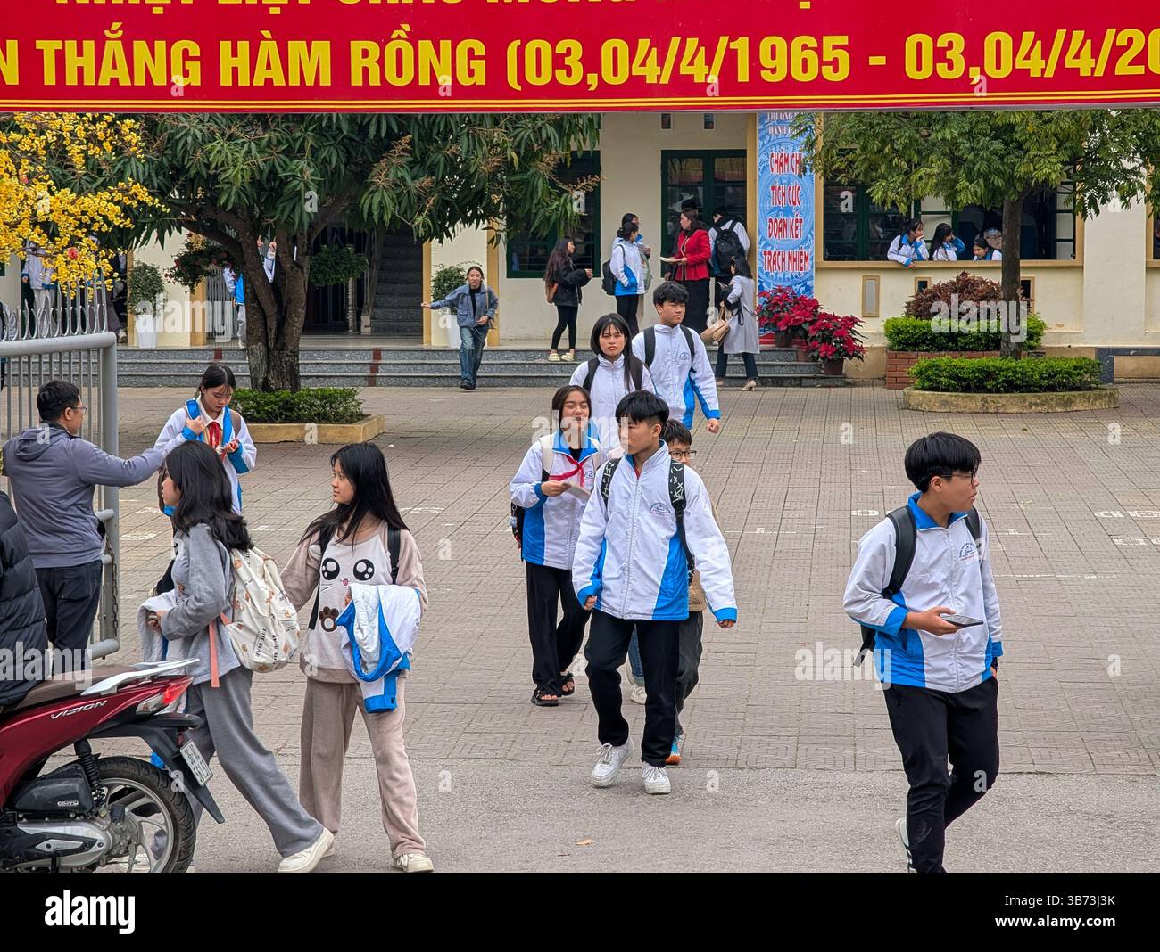 Gli studenti di una scuola media di Thanh Hoa, Vietnam, lasciano le loro classi dopo le lezioni il 18 marzo 2025, l'ingresso della scuola è abbellito da un divieto Foto Stock