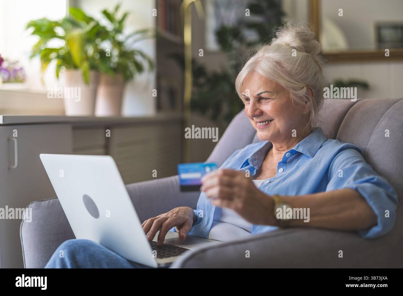 Donna a casa che fa acquisti online con un notebook Foto Stock
