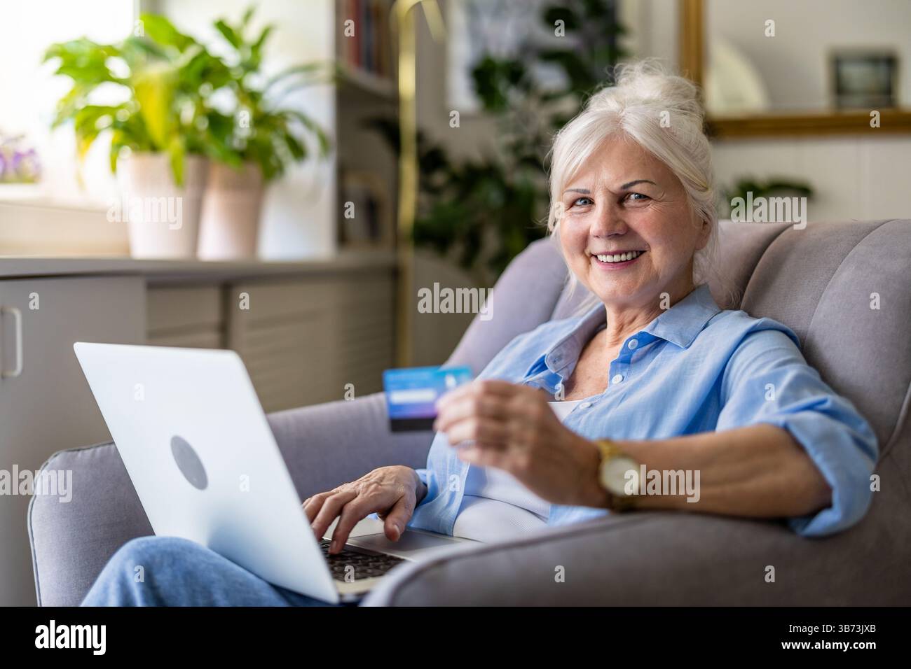 Donna a casa che fa acquisti online con un notebook Foto Stock