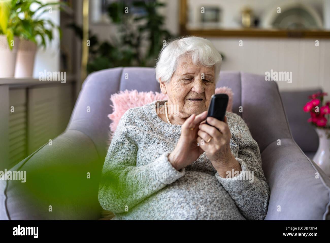 Senior donna utilizzando il telefono cellulare a casa Foto Stock