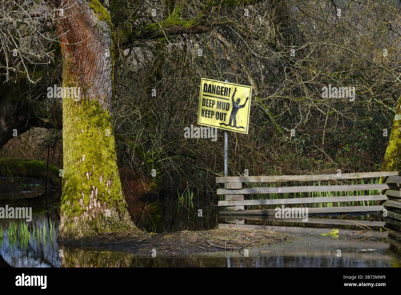 Cartello di pericolo "Deep Mud Keep Out" accanto allo stagno. Foto Stock