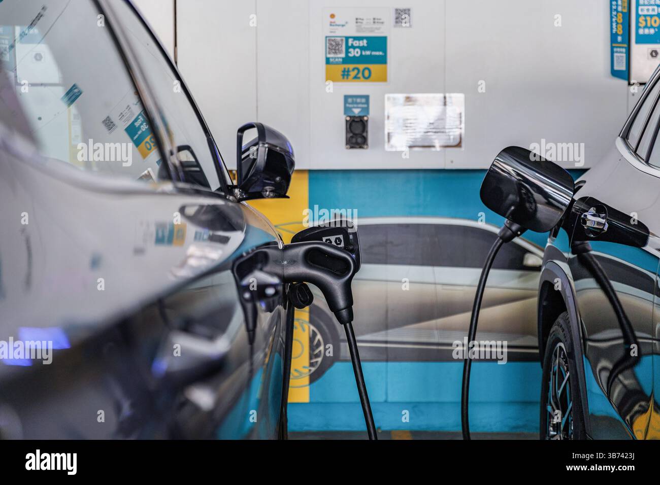 Due veicoli elettronici sono stati caricati presso la stazione Shell, una delle più grandi aziende energetiche del mondo. Secondo quanto riferito, la Shell sta valutando i meriti di una potenziale acquisizione della rivale BP, a seguito di un forte calo del valore di mercato di BP. Sebbene non sia stata fatta alcuna offerta formale, la mossa, se perseguita, potrebbe rimodellare il panorama energetico globale e affrontare un intenso controllo normativo. Foto Stock