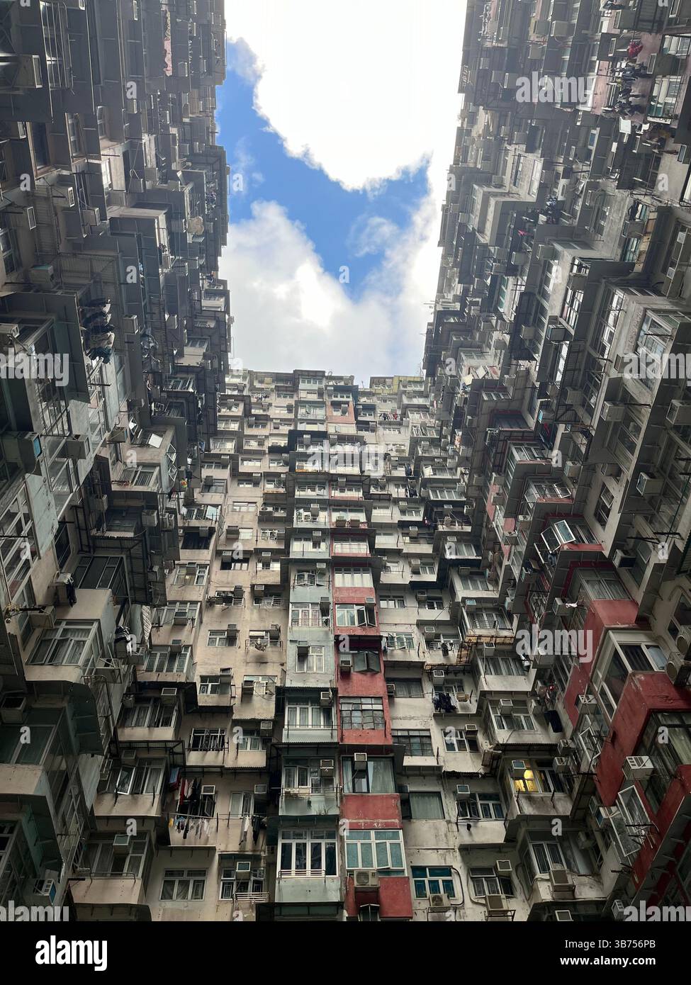 Edifici residenziali densamente affollati a Montane Mansion (Monster Building), Quarry Bay, Hong Kong, visti dal basso in una giornata luminosa e nuvolosa. - Immagine stock catturata con smartphone