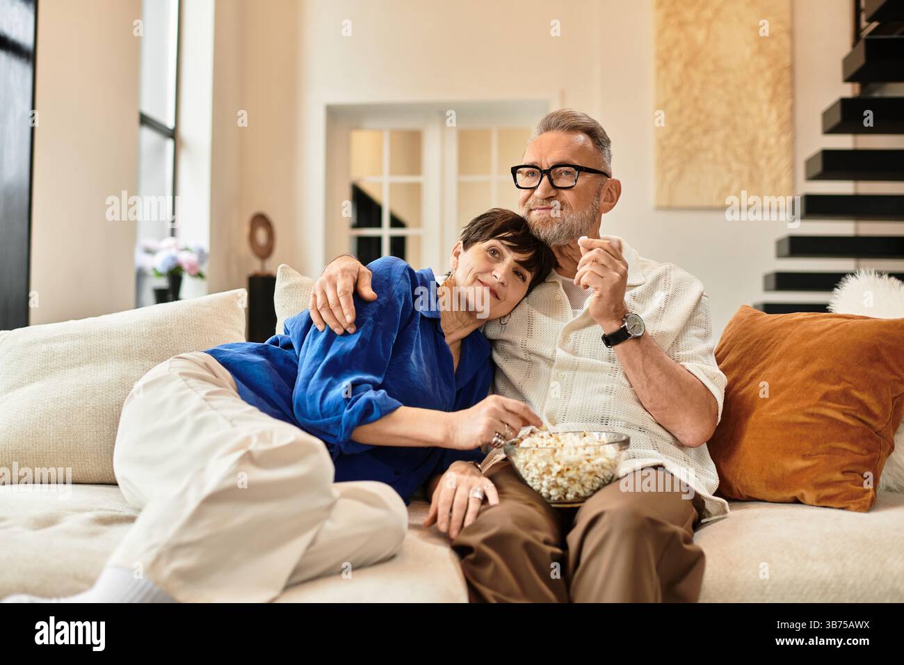 Questa coppia gioiosa sta condividendo una deliziosa serata insieme, rilassandosi a casa. Foto Stock