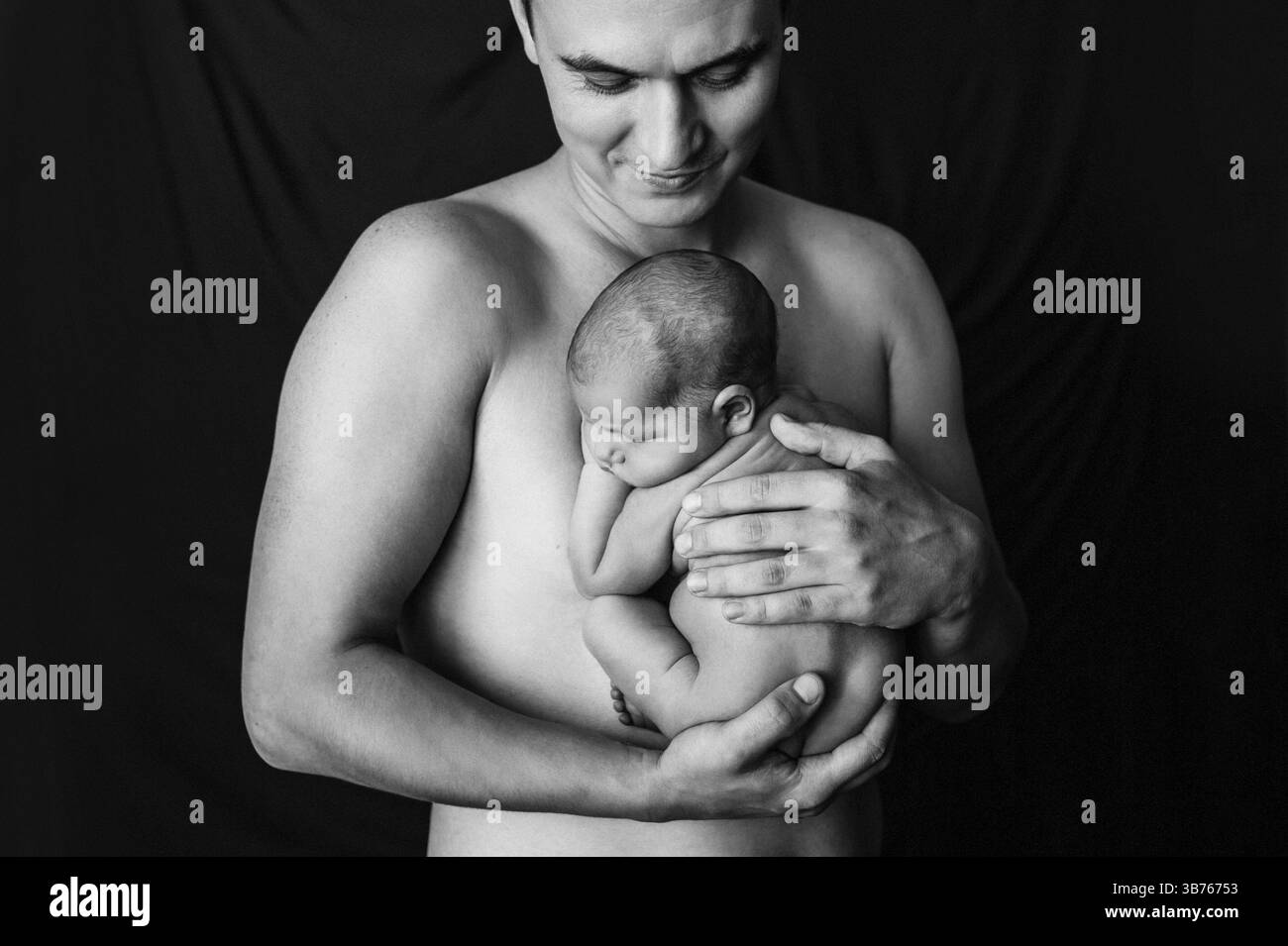 Padre che tiene in braccio la figlia appena nata a un servizio fotografico per neonati. Foto Stock