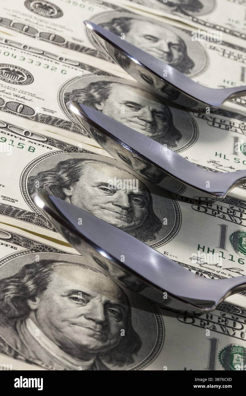 Cucchiai da acciaio inossidabile e US dollar banconote Foto Stock