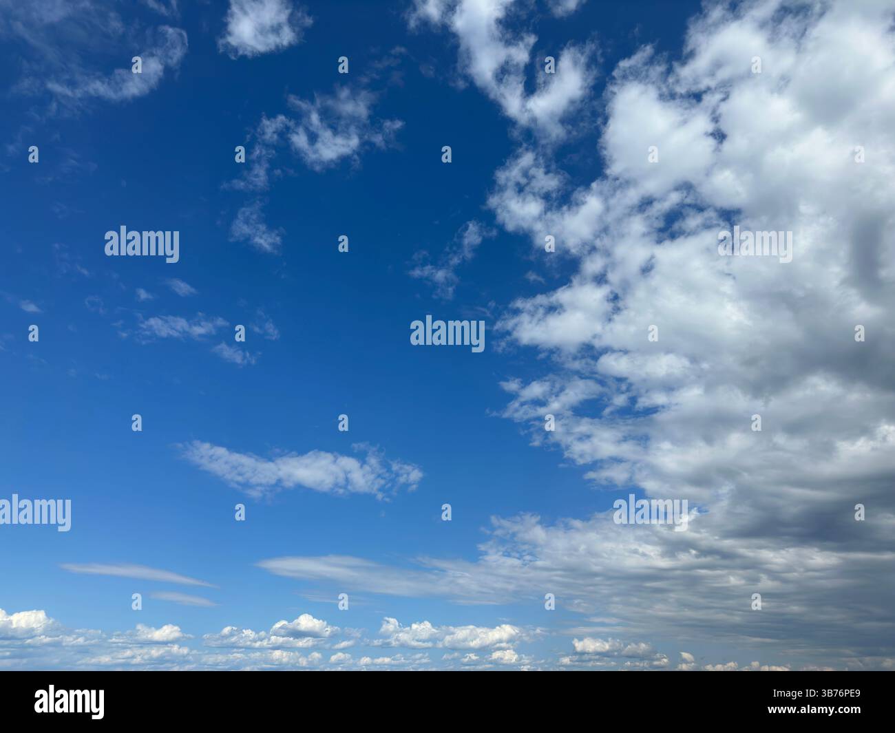 Cielo blu con soffici nuvole bianche sparse e un tocco di nuvole grigie. Foto Stock
