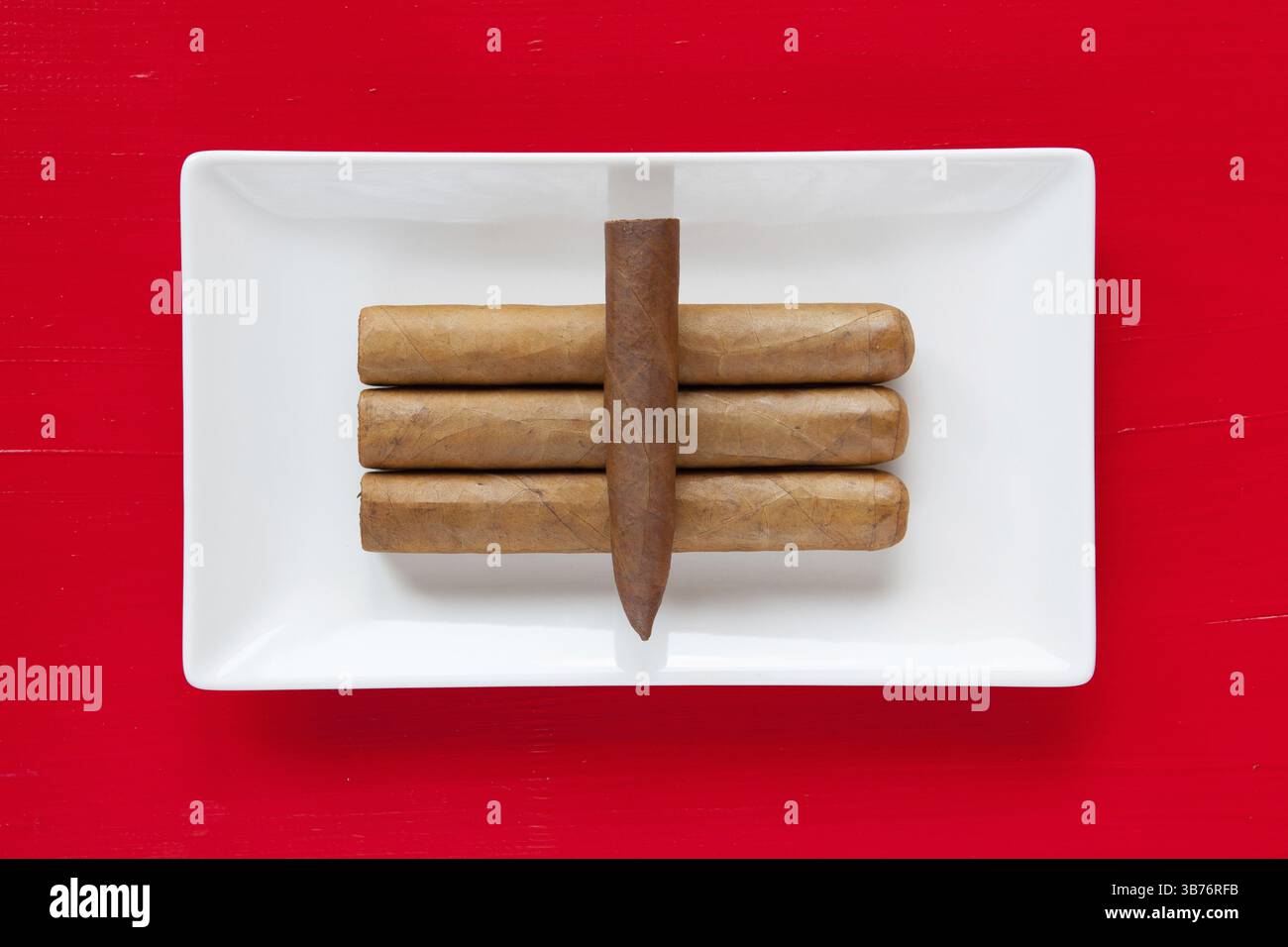 Bianco piatto in ceramica con lusso sigari cubani su sfondo rosso, rettangolo piatto Foto Stock