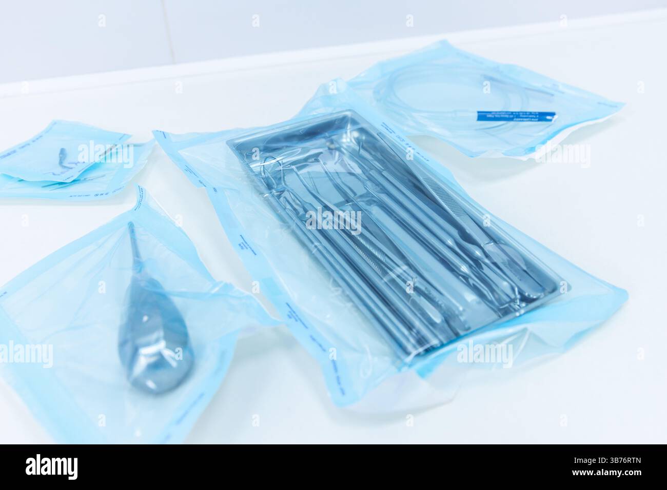 L'immagine mostra una varietà di strumenti e materiali medici sterili, meticolosamente confezionati e preparati per l'uso in procedure chirurgiche o cliniche Foto Stock