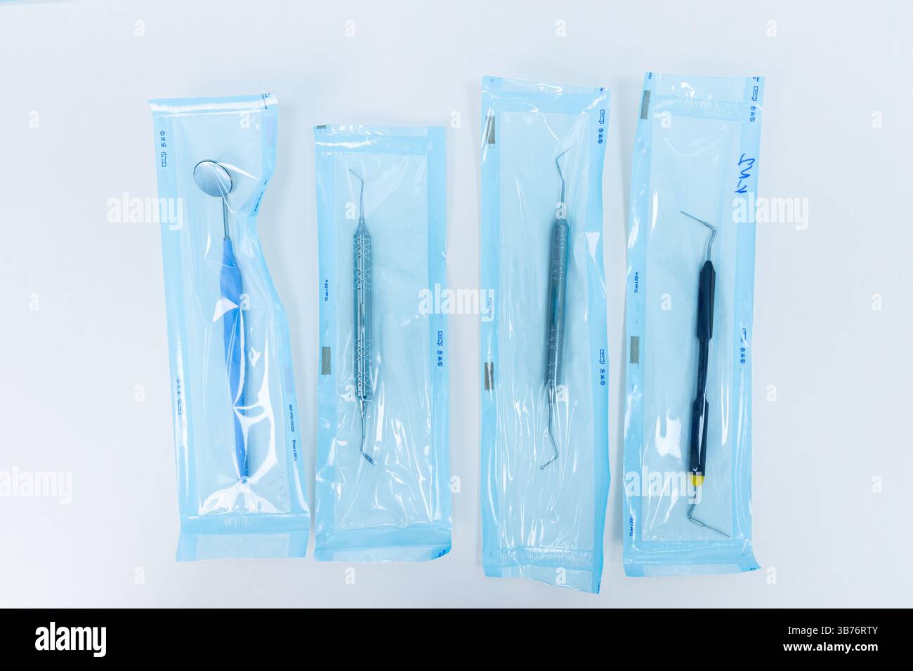 L'immagine mostra un set di quattro strumenti odontoiatrici confezionati in modo ordinato per un uso sicuro negli studi odontoiatrici, evidenziando l'importanza delle pratiche igieniche in o Foto Stock