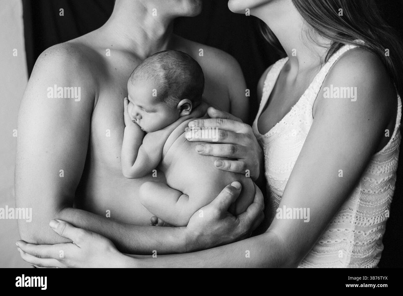 Madre e padre tengono in braccio il loro bambino appena nato a un servizio fotografico. Foto Stock