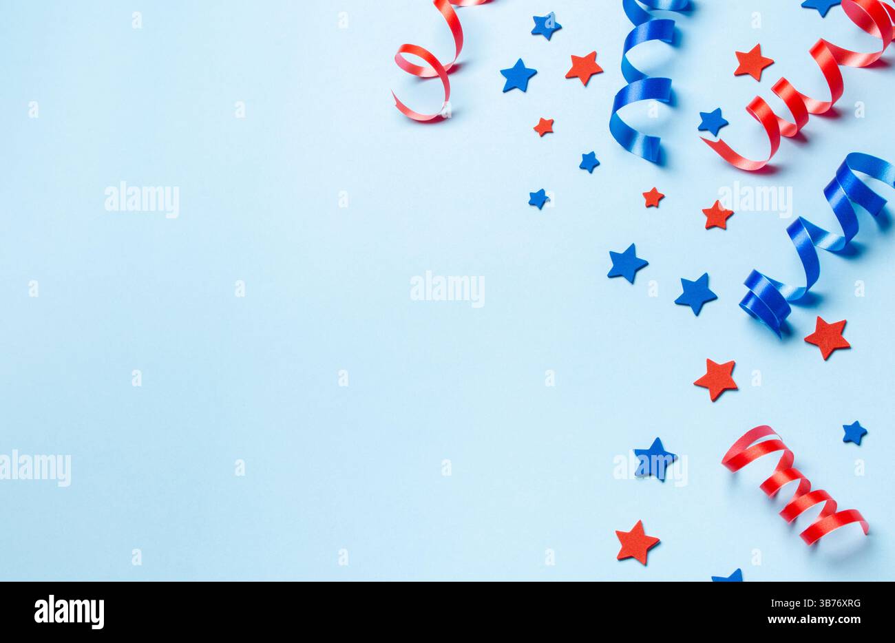 Confetti rosso e blu festivi con nastri su sfondo azzurro. Concetto del giorno dell'indipendenza Foto Stock