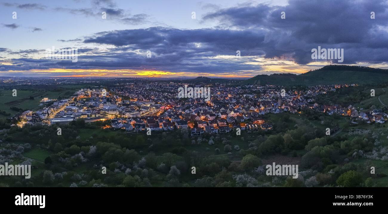 Piccola città al crepuscolo con luci accese e nuvole scure sulle colline ondulate, Korb-Steinreinach, Rems Valley, Baden-Wuerttemberg, Germania, Europa Foto Stock