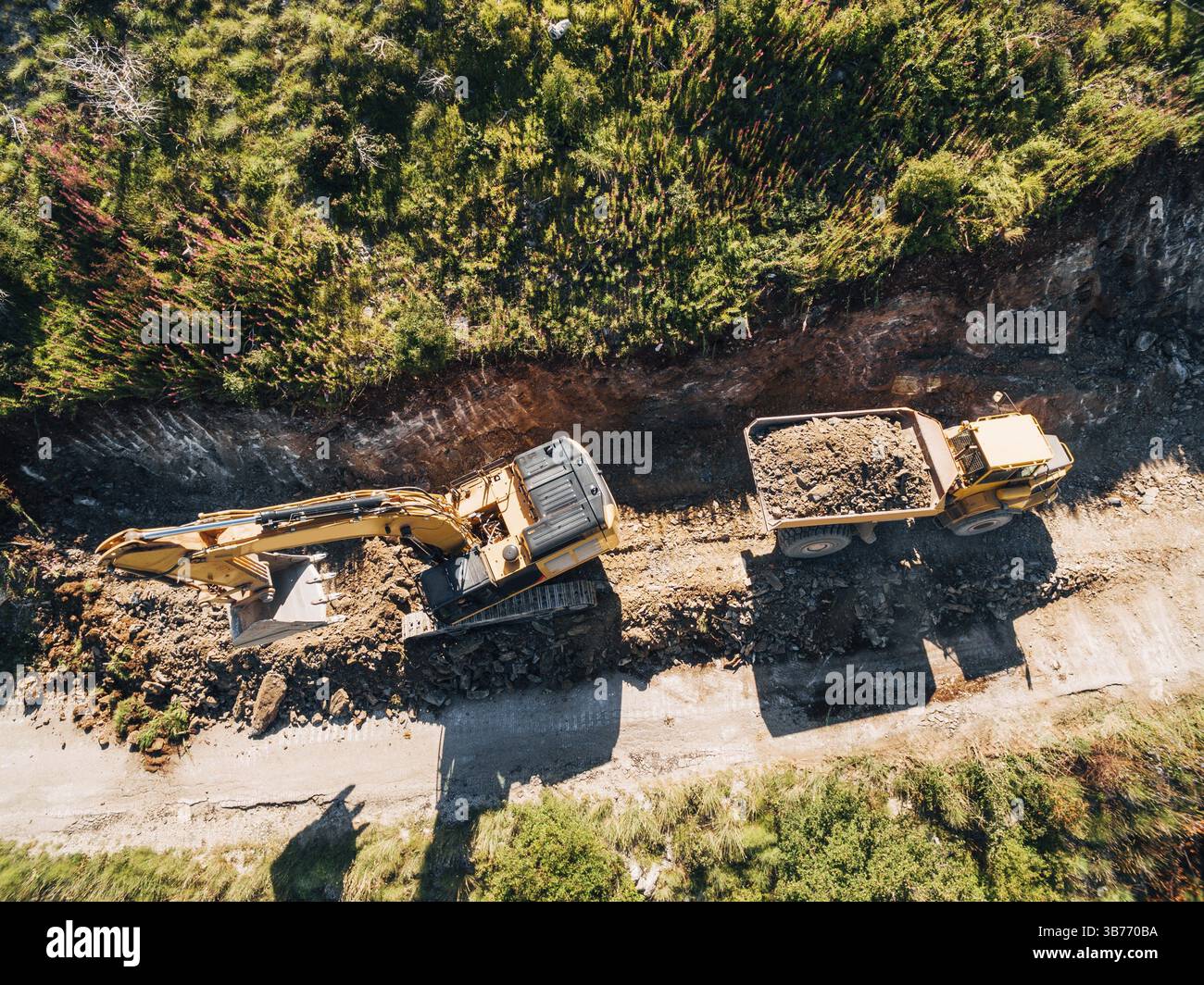 Il trattore cingolato giallo carica un veicolo da cava con sabbia. Vista aerea . Foto Stock